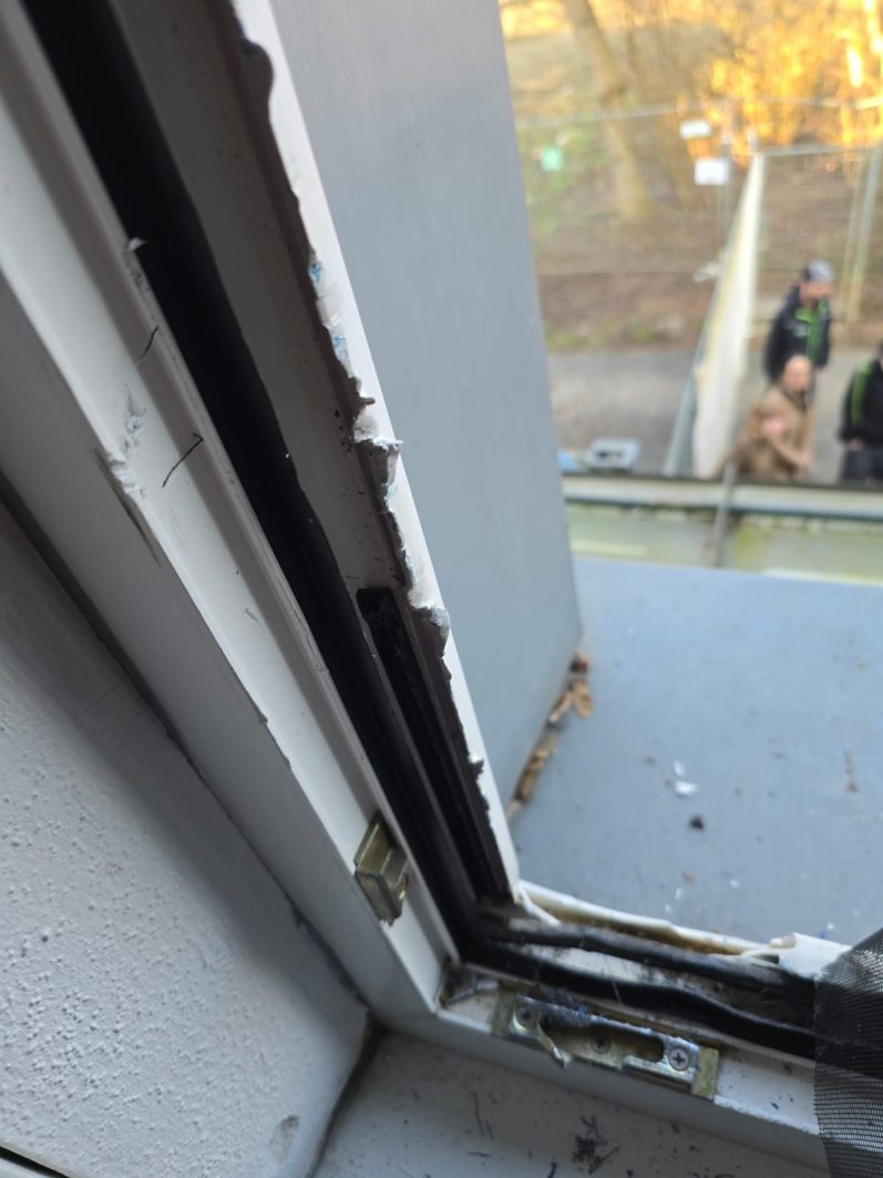 Beschädigte Fensterrahmenkante mit sichtbarem Lackabblätterung und Schmutz.