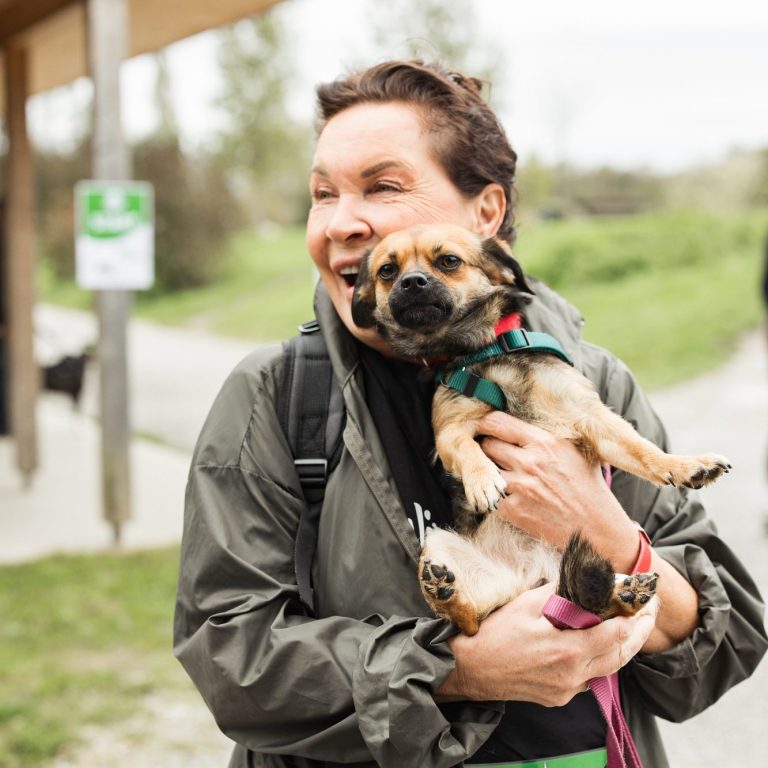 Frau hält einen kleinen Tierheim-Hund in den Armen und lächelt beim Tierschutzlauf2024.